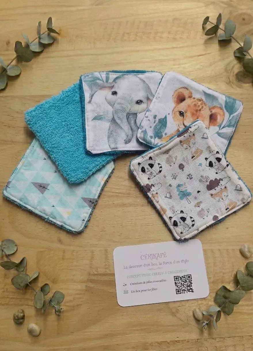 Quatre lingettes lavables pour bébé, imprimées éléphant, lionceau, panda et renard, associées à des carrés d'éponge turquoise et menthe