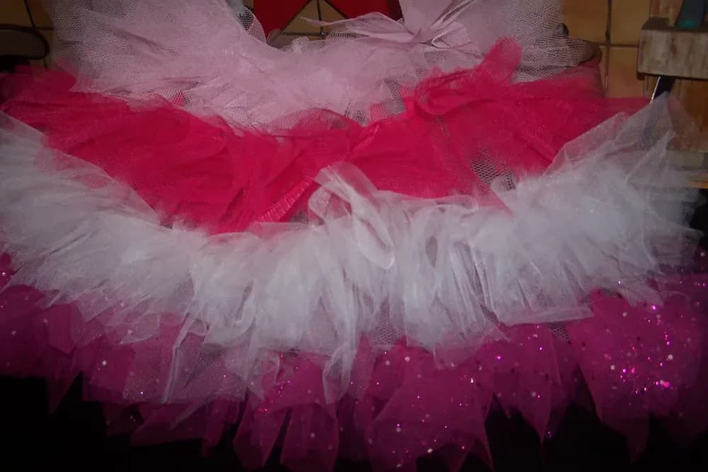Gros plan sur une jupe tutu à étages alternant le tulle rose fuchsia et le tulle blanc, le volant du bas pailleté