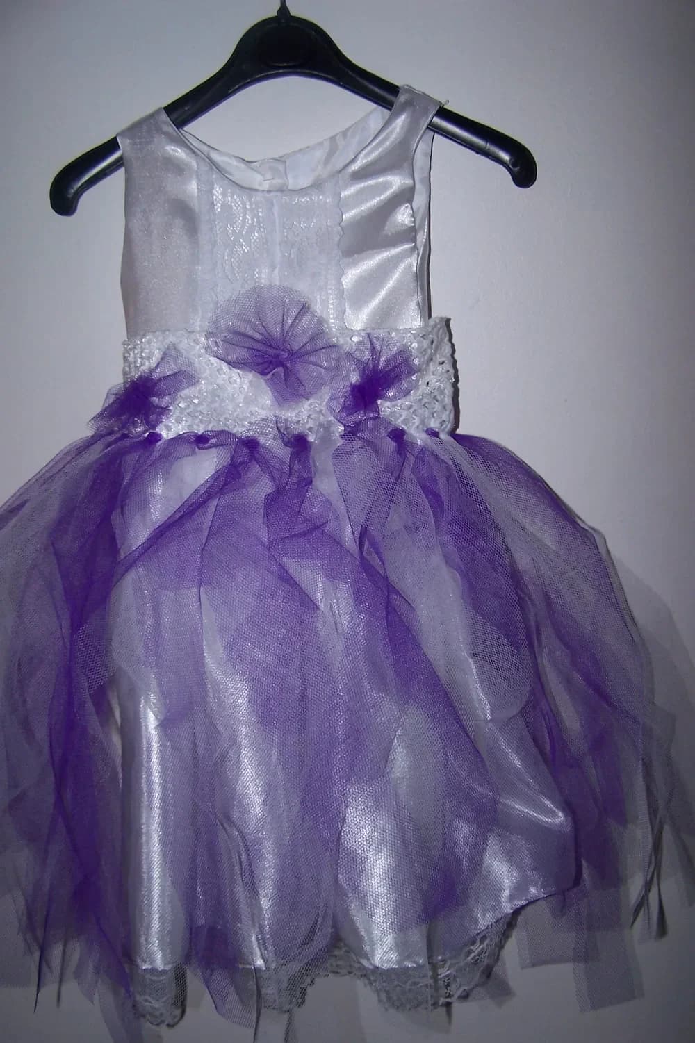 Robe sur un cintre noir : corsage en satin blanc, ceinture de dentelle blanche ornée d'un nœud en tulle violet et jupe en tulle violet sur un jupon de satin blanc