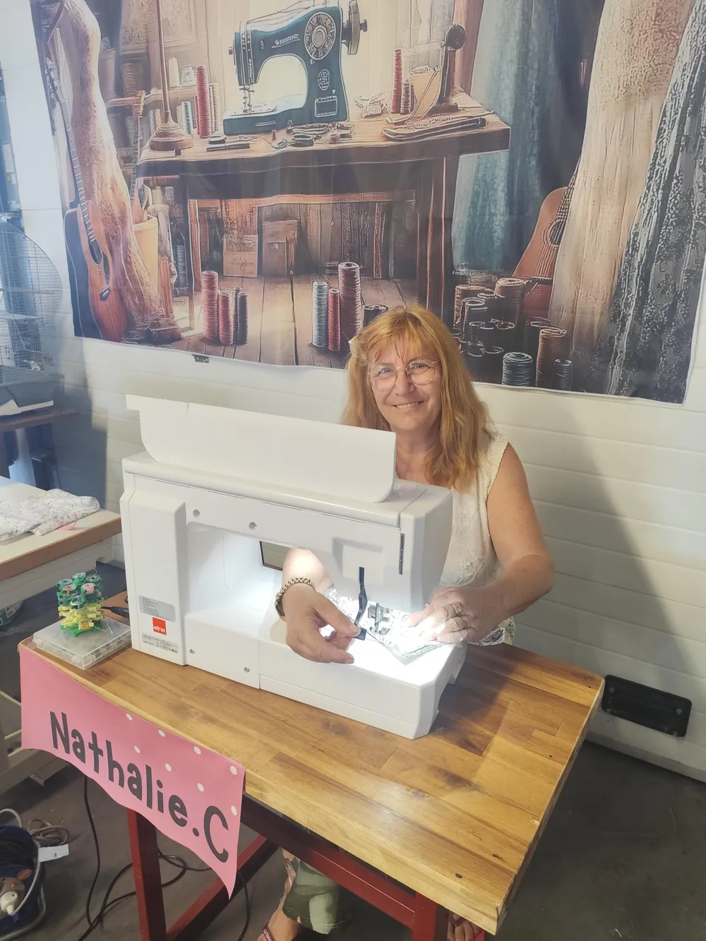 Nathalie, créatrice de CÉKIKAFÉ, souriante devant sa machine à coudre dans son atelier