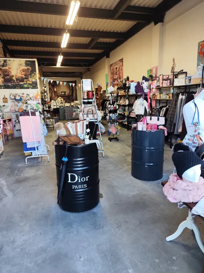 Allée de la boutique avec présentoirs en tonneau « Dior Paris » et portants de vêtements et accessoires bébé
