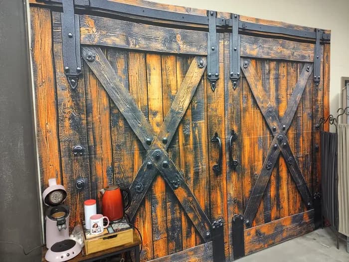 Décor mural en trompe-l'œil représentant une porte de grange en bois, avec cafetière et bouilloire rouge