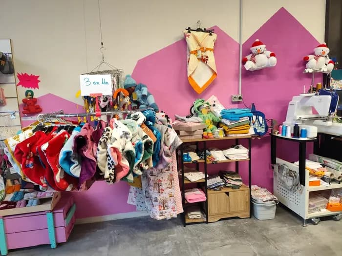 Mur rose avec gigoteuses et bavoirs suspendus, doudous en peluche et machine à coudre Brother