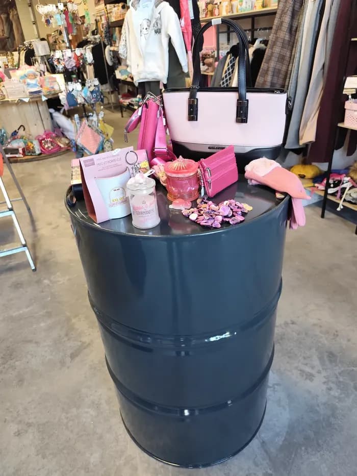 Tonneau gris présentant un sac à main rose et blanc, un portefeuille et des accessoires roses