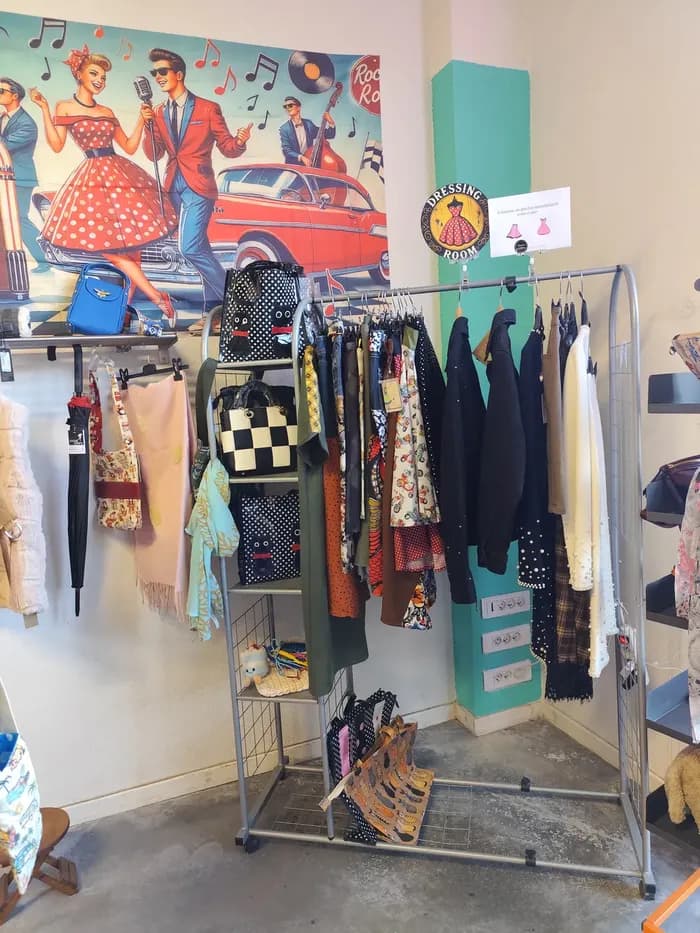 Portant de vêtements sous une fresque rock'n'roll pin-up, près d'une enseigne « Dressing Room »